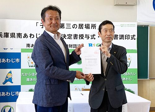 決定書授与の様子&emsp;守本市長（右）、菅原理事長（左）