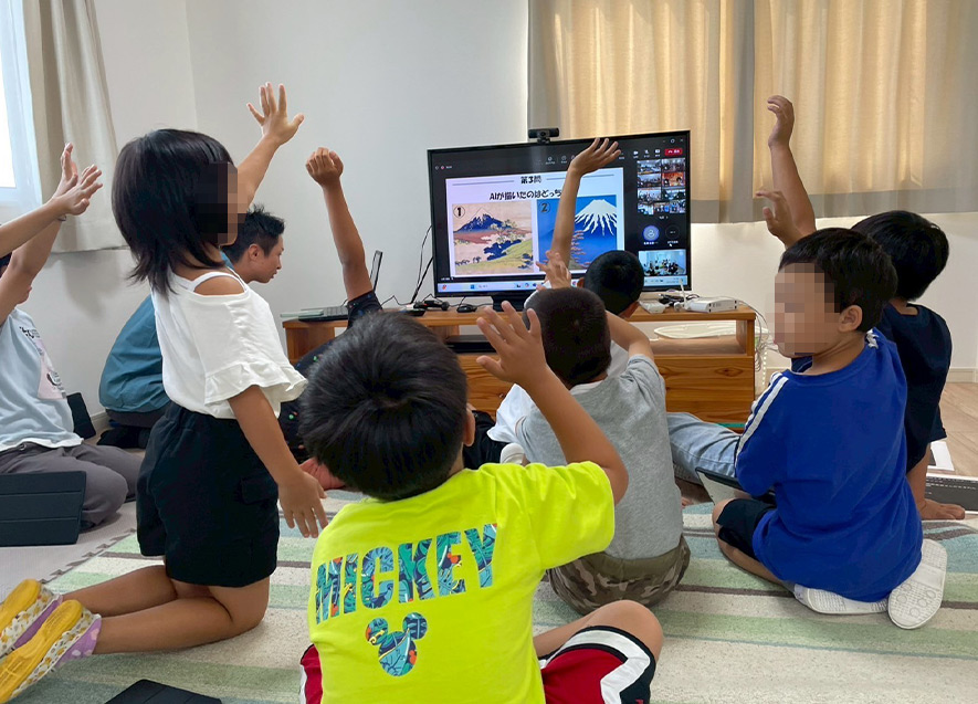  
											正解だと思う方に元気よく手を挙げる子どもたち