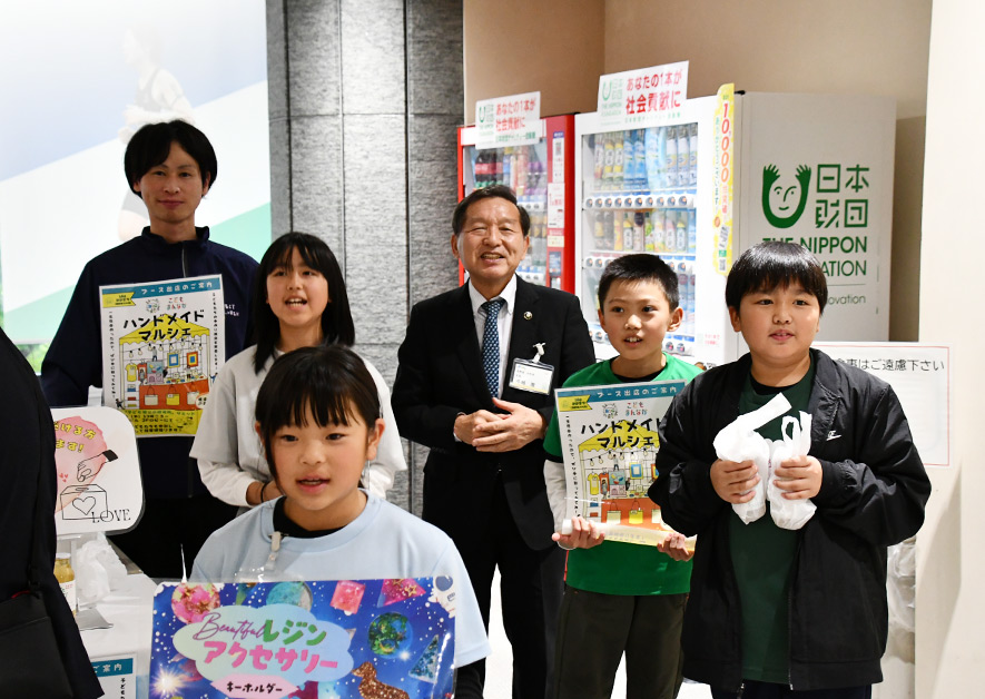 大町市・牛越市長と一緒に記念撮影する販売ブースの子どもたち