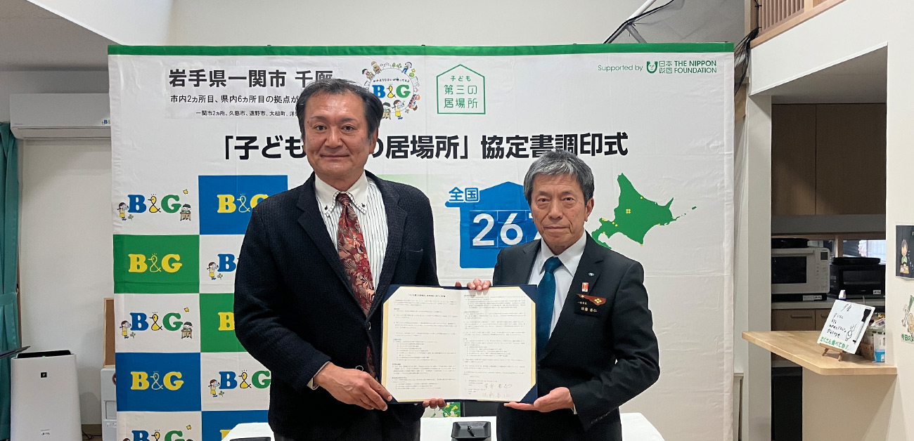 佐藤市長と菅原理事長が調印書をもっている様子