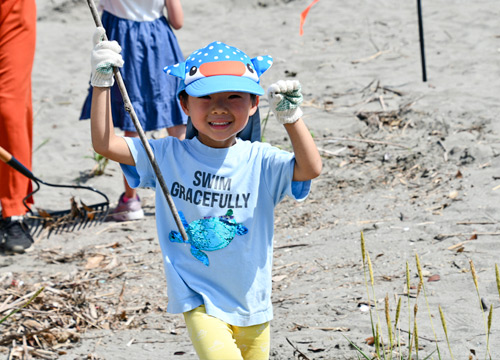 一生懸命活動に参加してくれた男の子。左手に流木、右手には小さなゴミを握りしめてゴミ捨て場に向かう一コマ