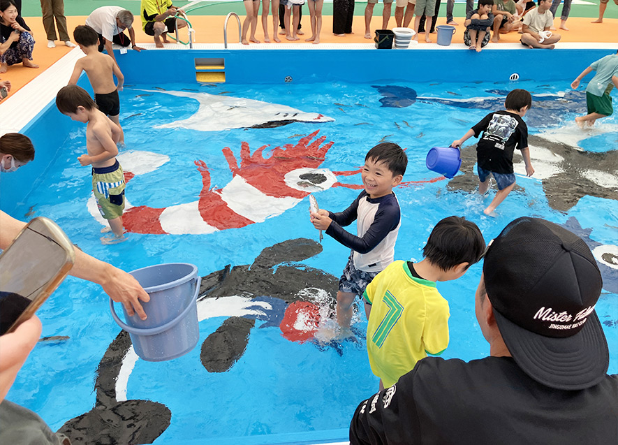 イワナを捕まえ笑顔を見せる子ども