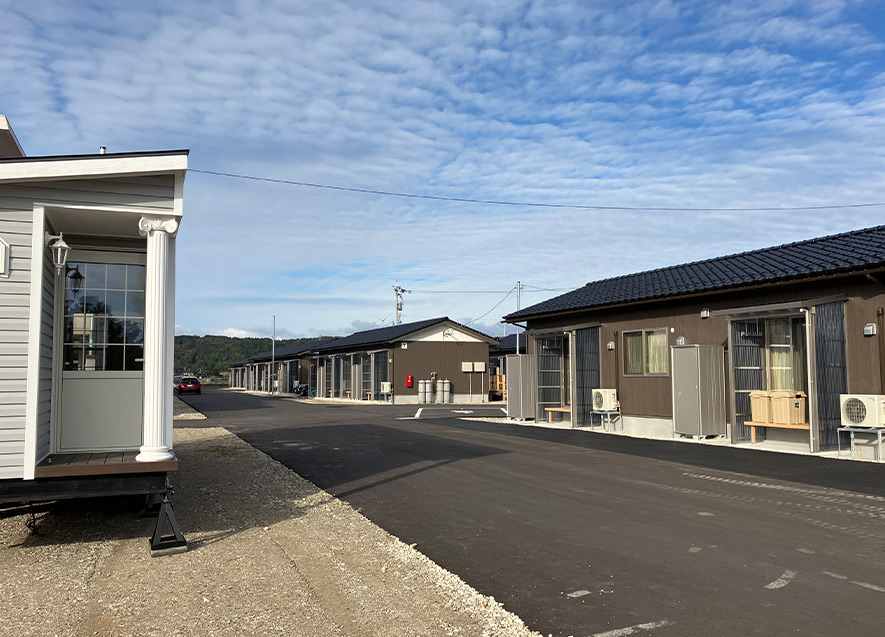 店舗から道路を挟んで仮設住宅が建ち並ぶ